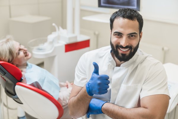 Smiling dentist giving a thumbs-up beside a patient in a modern dental clinic for cosmetic dentistry in Stuart